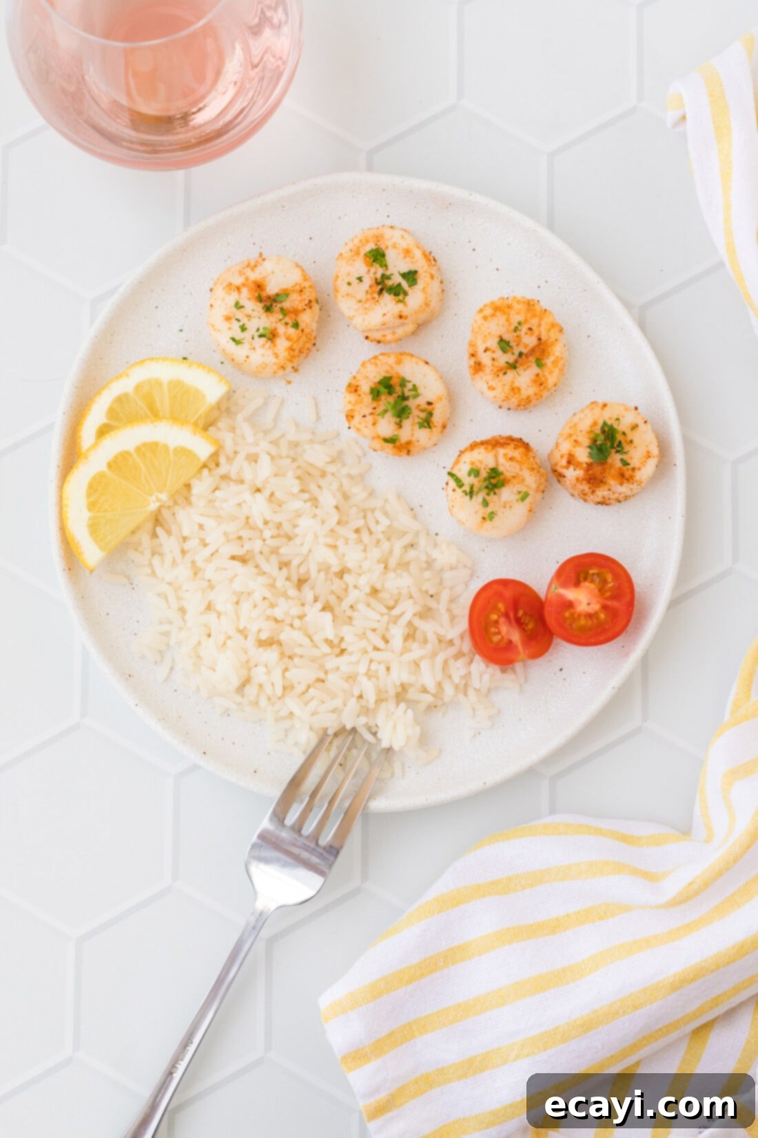 Perfect Air Fryer Scallops 8 Air Fryer Scallops served on a white plate with lemon wedges and fresh herbs