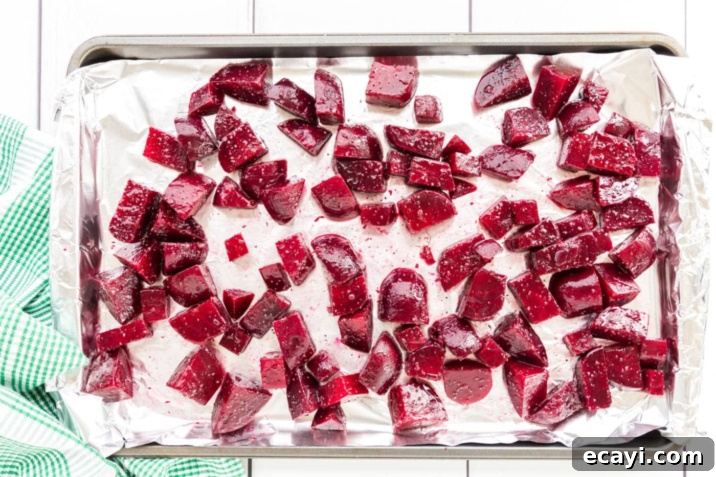 Caramelized Beet Perfection 7 Chopped and seasoned beet pieces spread in a single layer on a foil-lined roasting pan, ready for the oven
