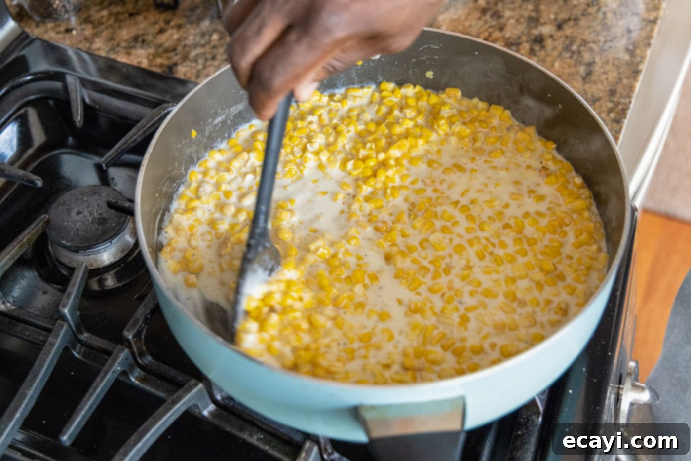 Golden Comfort Corn 9 stirring creamed corn in a skillet to thicken