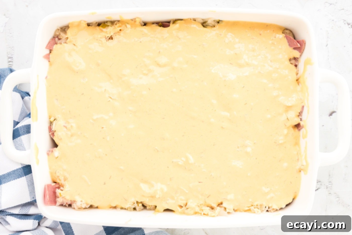 Ultimate Reuben Casserole Bake 12 A creamy layer of Thousand Island dressing mixture being spread over the sauerkraut and pickle layer in the Reuben casserole.