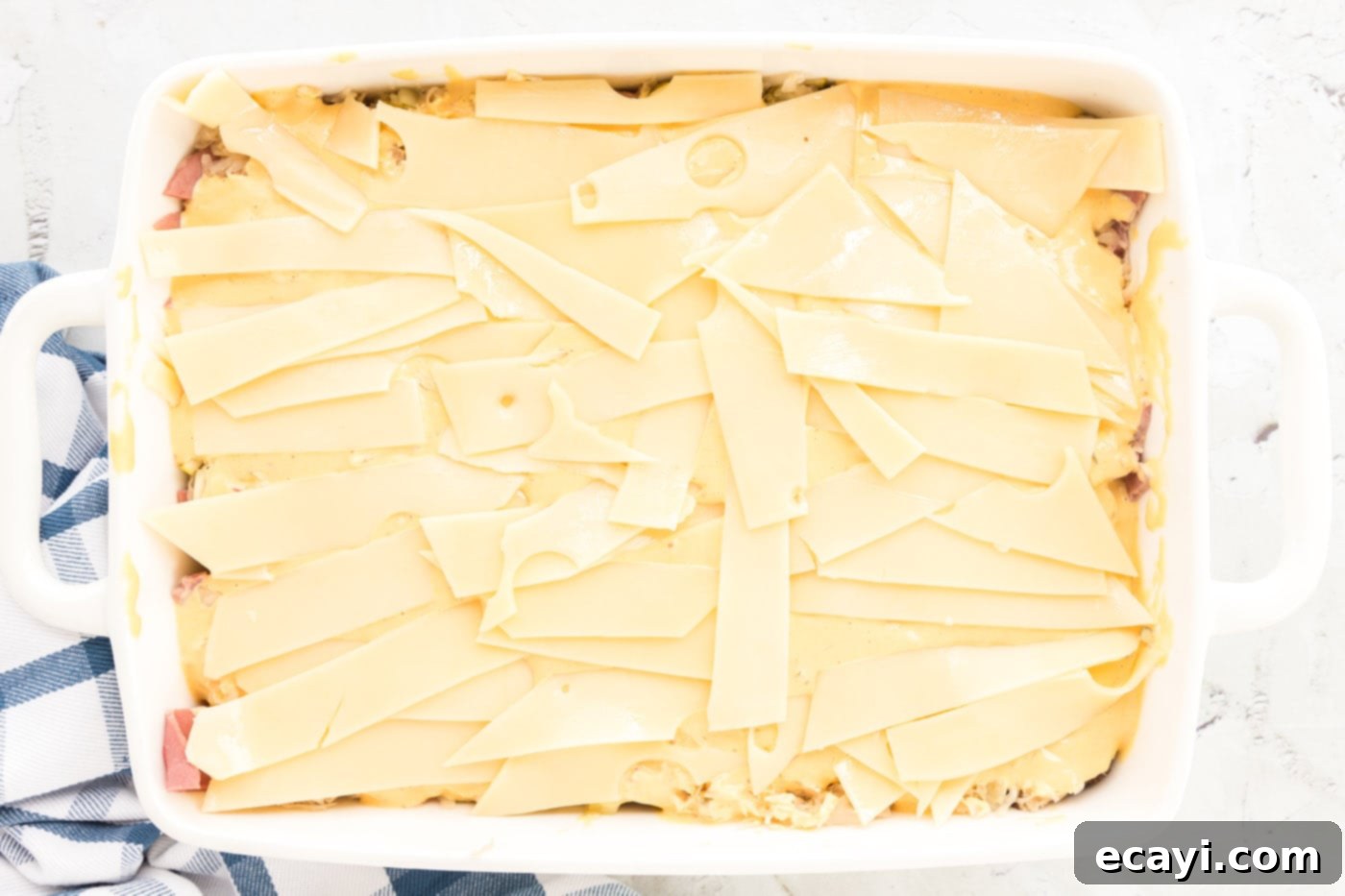 Ultimate Reuben Casserole Bake 13 Strips of Swiss cheese laid out over the Thousand Island dressing layer in the baking dish.