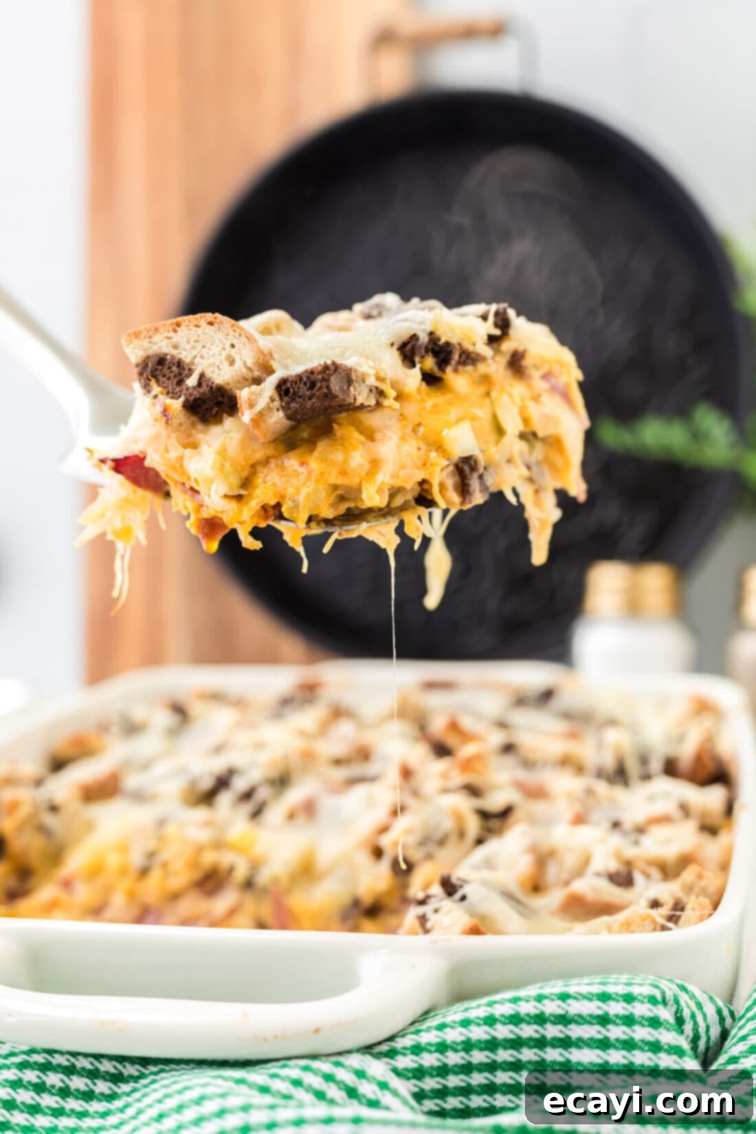 Ultimate Reuben Casserole Bake 3 A serving of Reuben Casserole being scooped from the pan with a spatula, revealing its rich, cheesy layers and appealing texture.