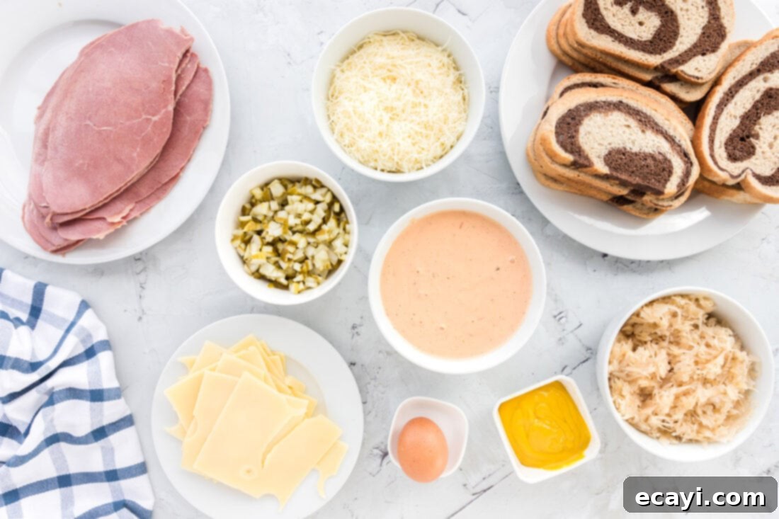 Ultimate Reuben Casserole Bake 4 A flat lay photograph displaying all the fresh ingredients needed for Reuben Casserole, including marble rye bread, sliced corned beef, Swiss cheese, sauerkraut, pickles, and Thousand Island dressing.