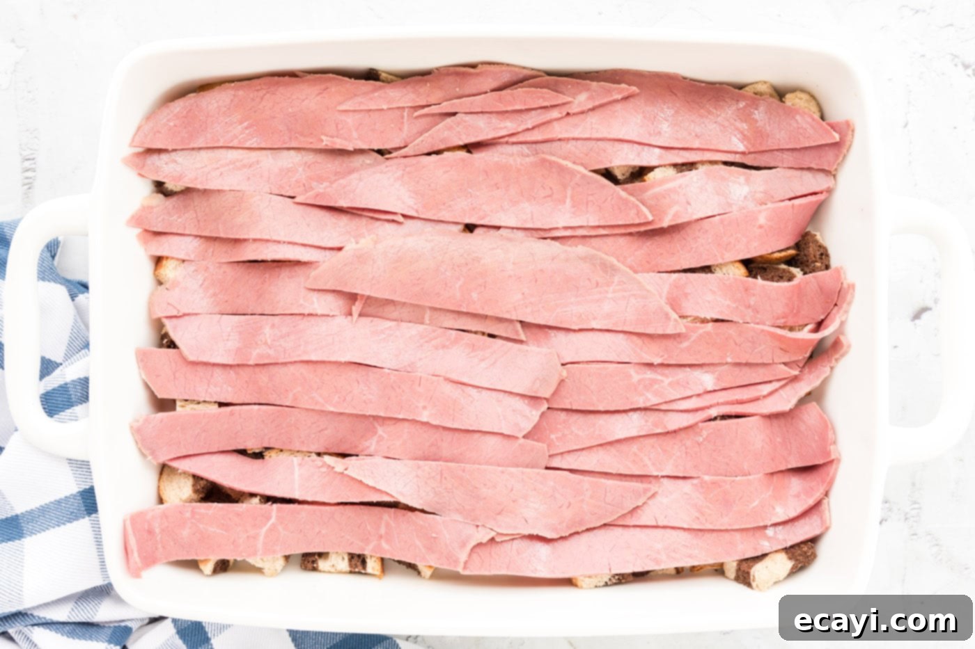 Ultimate Reuben Casserole Bake 10 A layer of thinly sliced corned beef strips carefully arranged over the bread cubes in the baking dish.