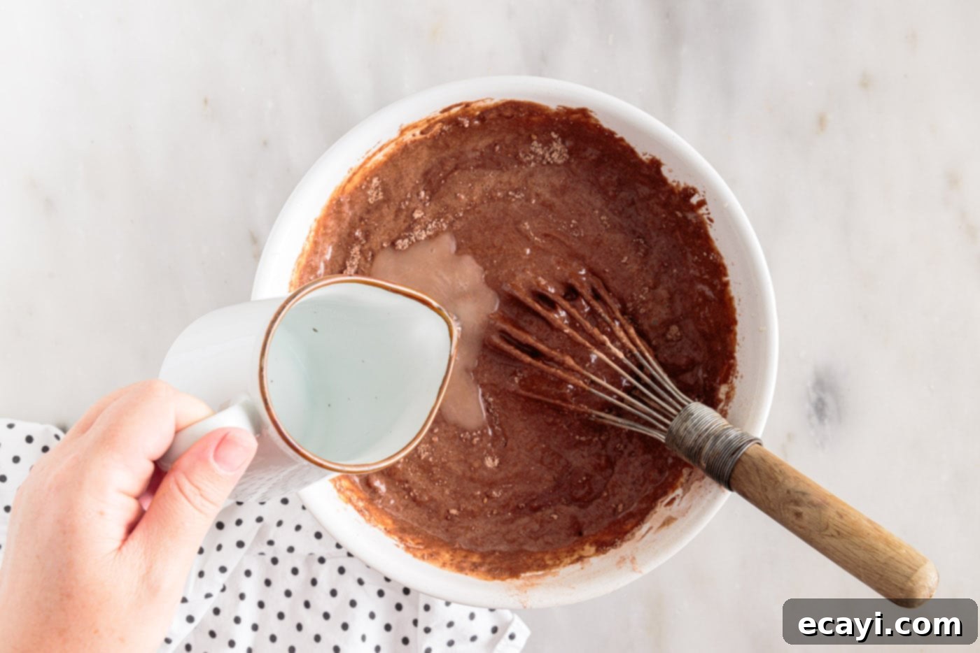 Velvet Moisture Cake 7 hot water being carefully added to the thick chocolate cake batter in a bowl