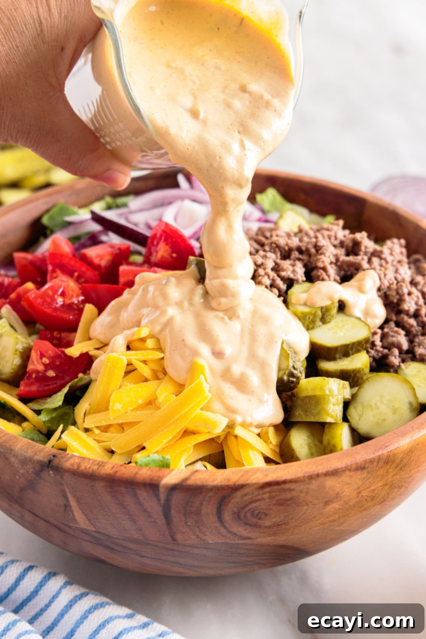 Deconstructed Big Mac Salad 9 pouring big mac sauce over the mixed salad, ready to be tossed