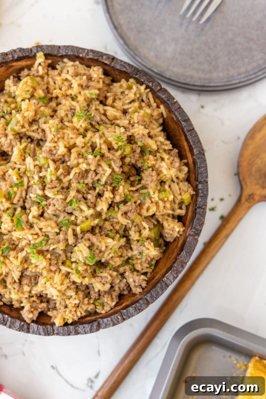 Soulful Louisiana Rice 2 A brown bowl filled with delicious Cajun Dirty Rice, garnished with fresh herbs.