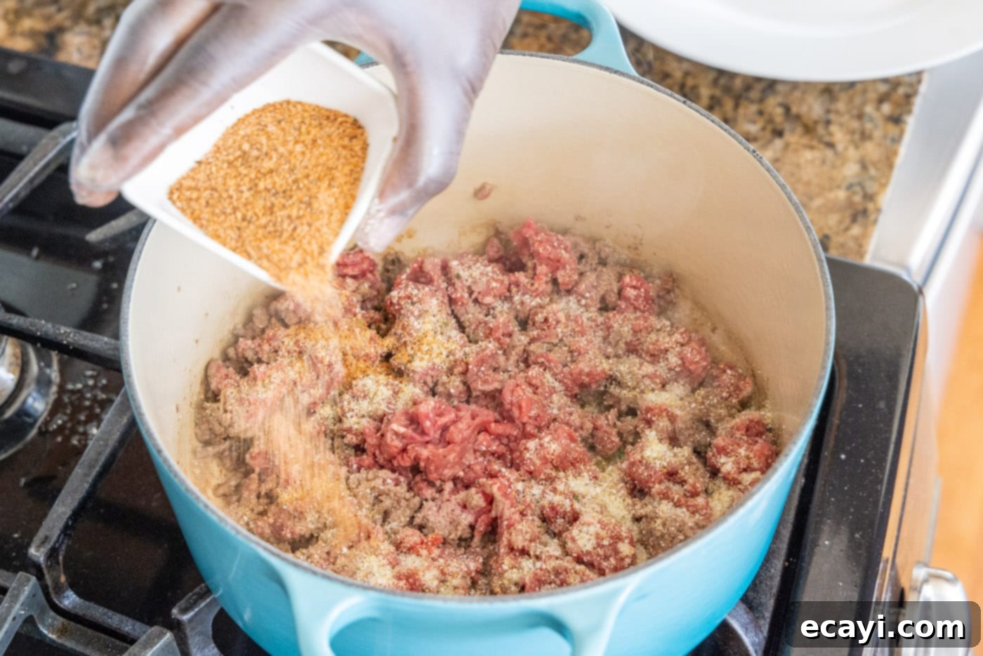 Soulful Louisiana Rice 6 Sprinkling Cajun seasoning over ground beef as it browns in a Dutch oven.