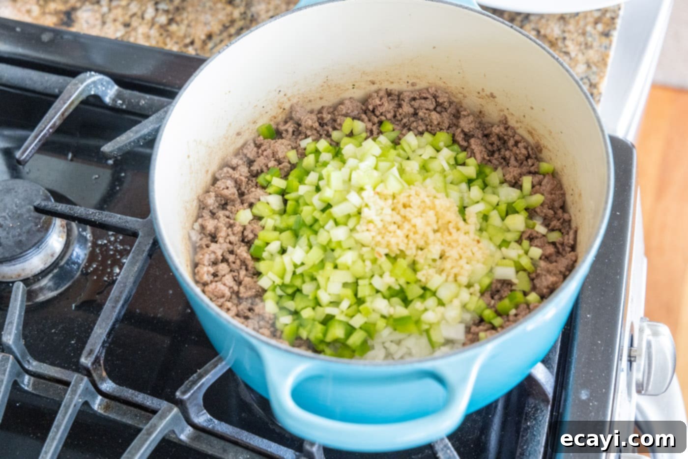 Soulful Louisiana Rice 7 Adding minced garlic to the mixture of ground beef, celery, onion, and peppers in the Dutch oven.