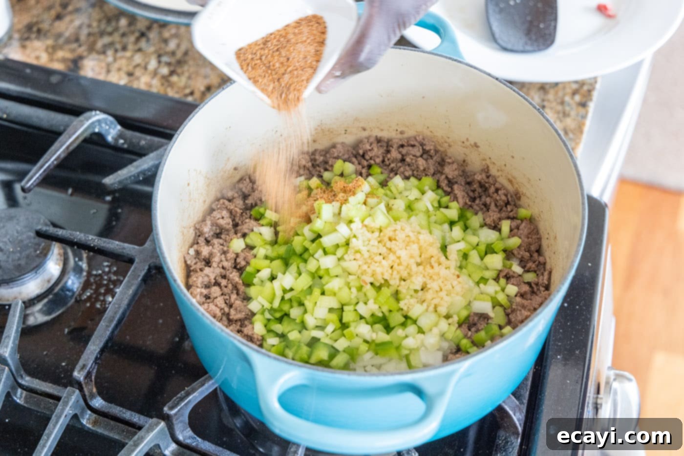 Soulful Louisiana Rice 8 Adding more Cajun seasoning to the dirty rice mixture in a Dutch oven for enhanced flavor.