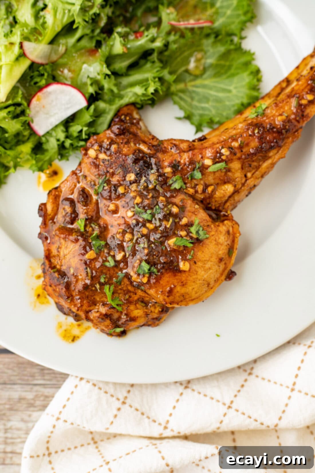 Succulent Veal Chops 2 A perfectly cooked veal chop on a white plate, served alongside a fresh green salad, highlighting its golden crust and juicy interior.