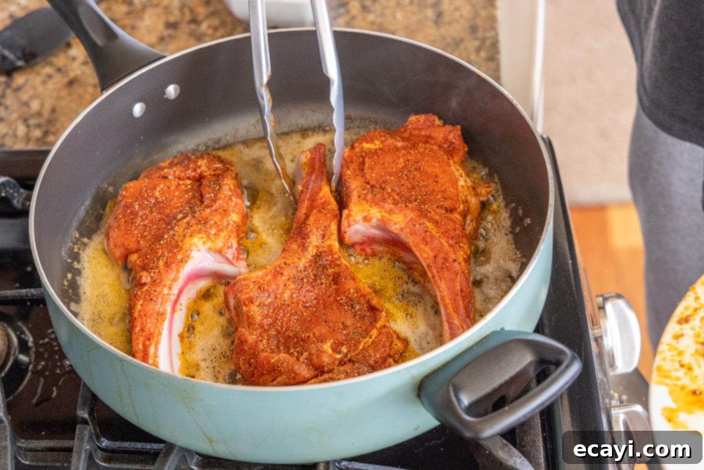 Succulent Veal Chops 7 Two thick veal chops sizzling and developing a golden-brown crust in a hot skillet with melted butter.
