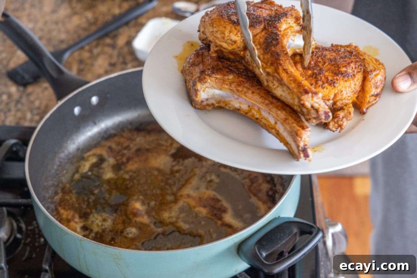 Succulent Veal Chops 9 Tongs lifting a perfectly seared veal chop from the hot skillet, showing the delicious crust.