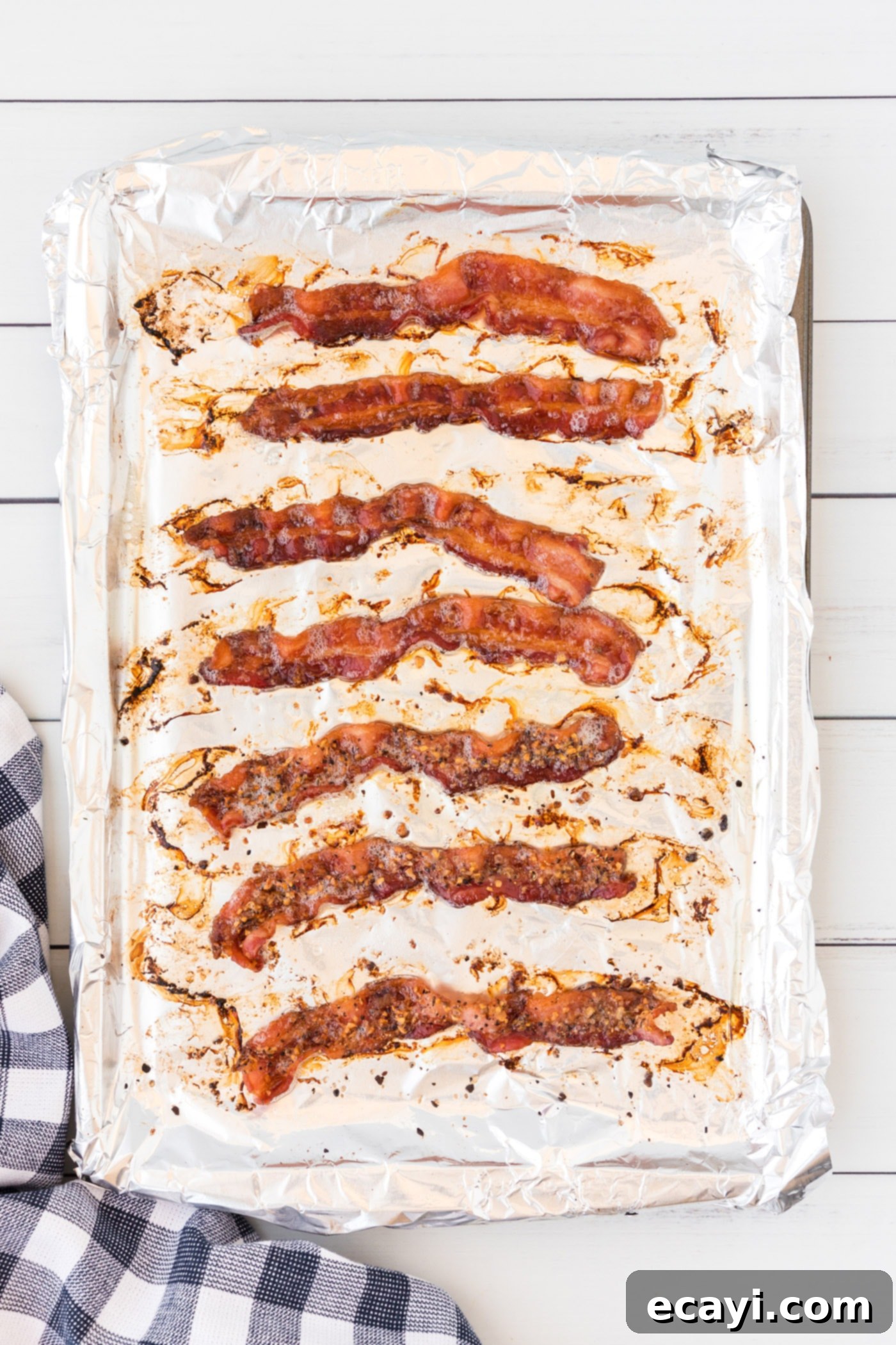 Perfect Crispy Oven Bacon 6 Crispy bacon slices cooking in the oven on a baking sheet, golden brown and perfectly rendered