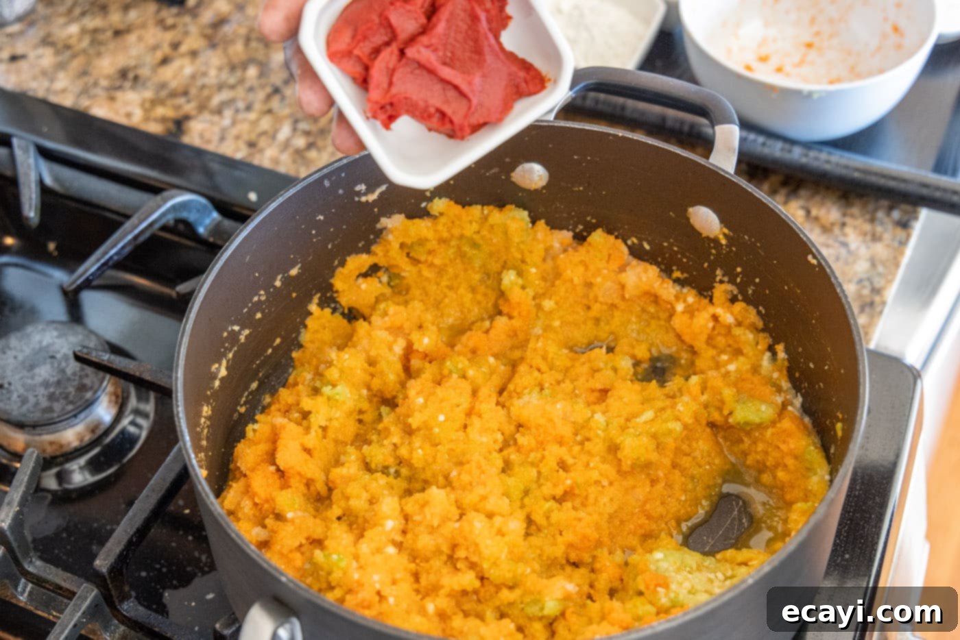 Rich Lobster Bisque 6 adding vibrant red tomato paste to sautéed vegetables in a Dutch oven