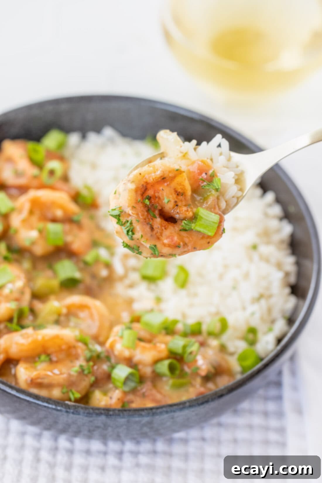 Authentic Cajun Shrimp Etouffee 13 A fork lifts a generous bite of shrimp etouffee, showcasing its rich sauce and succulent shrimp.