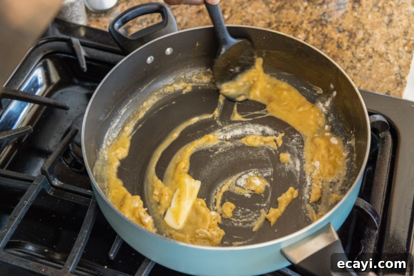 Authentic Cajun Shrimp Etouffee 8 A spatula stirring the deepening roux and vegetables in a skillet for shrimp etouffee.