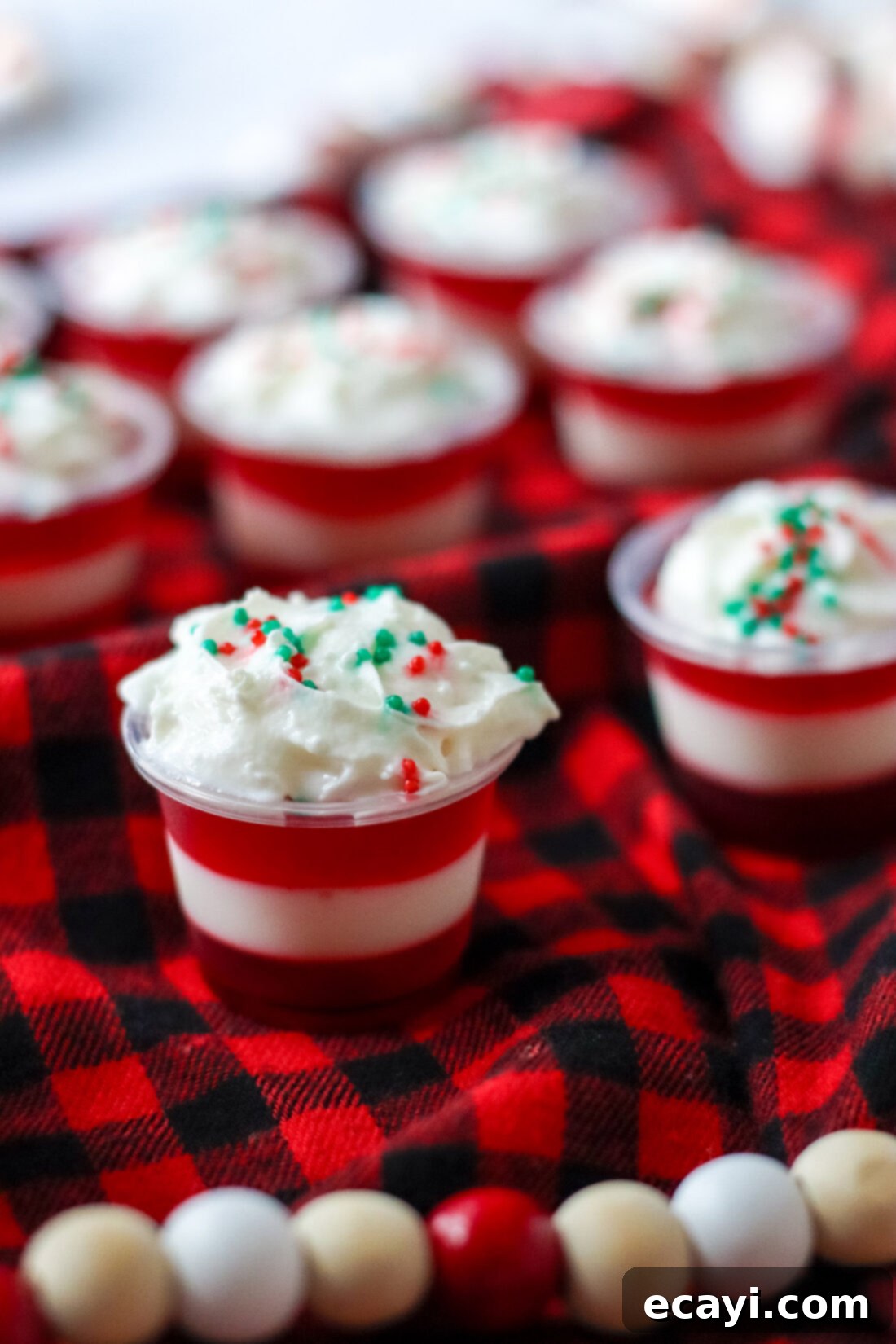 Peppermint Swirl Shooters 3 Candy Cane Jello Shots topped with fluffy whipped cream and festive sprinkles