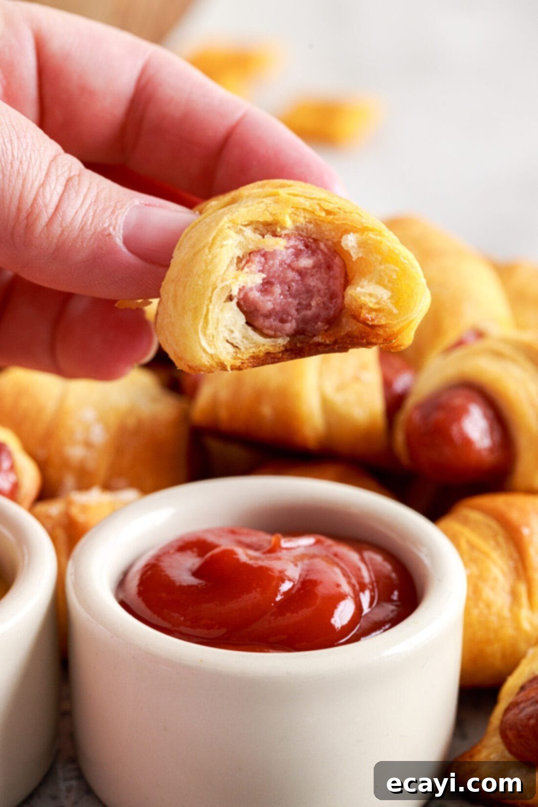 Swaddled Sausages 3 Pigs in a Blanket with a bite taken out, showing the sausage inside