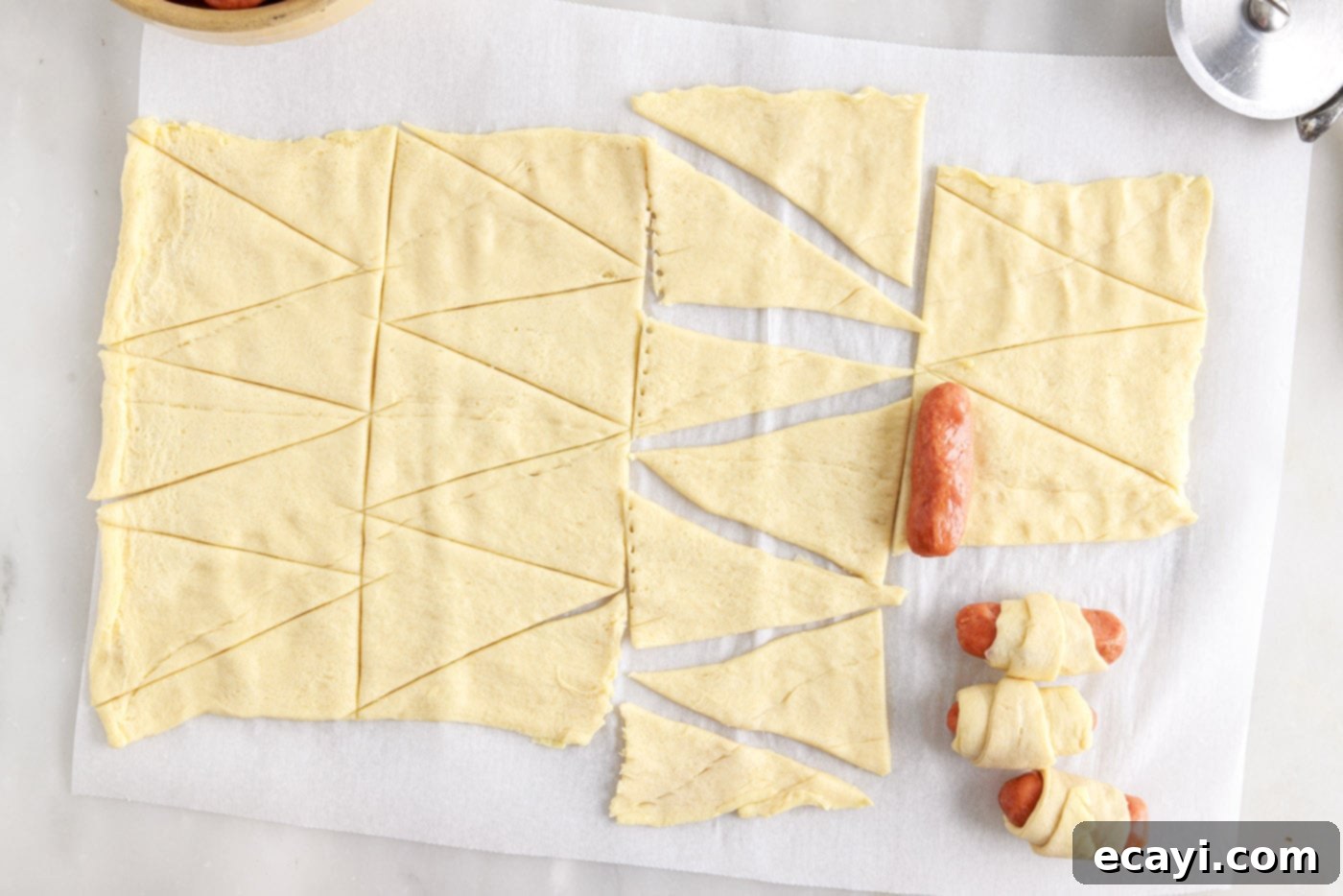 Swaddled Sausages 6 rolling a cocktail sausage into the wide end of a crescent dough triangle