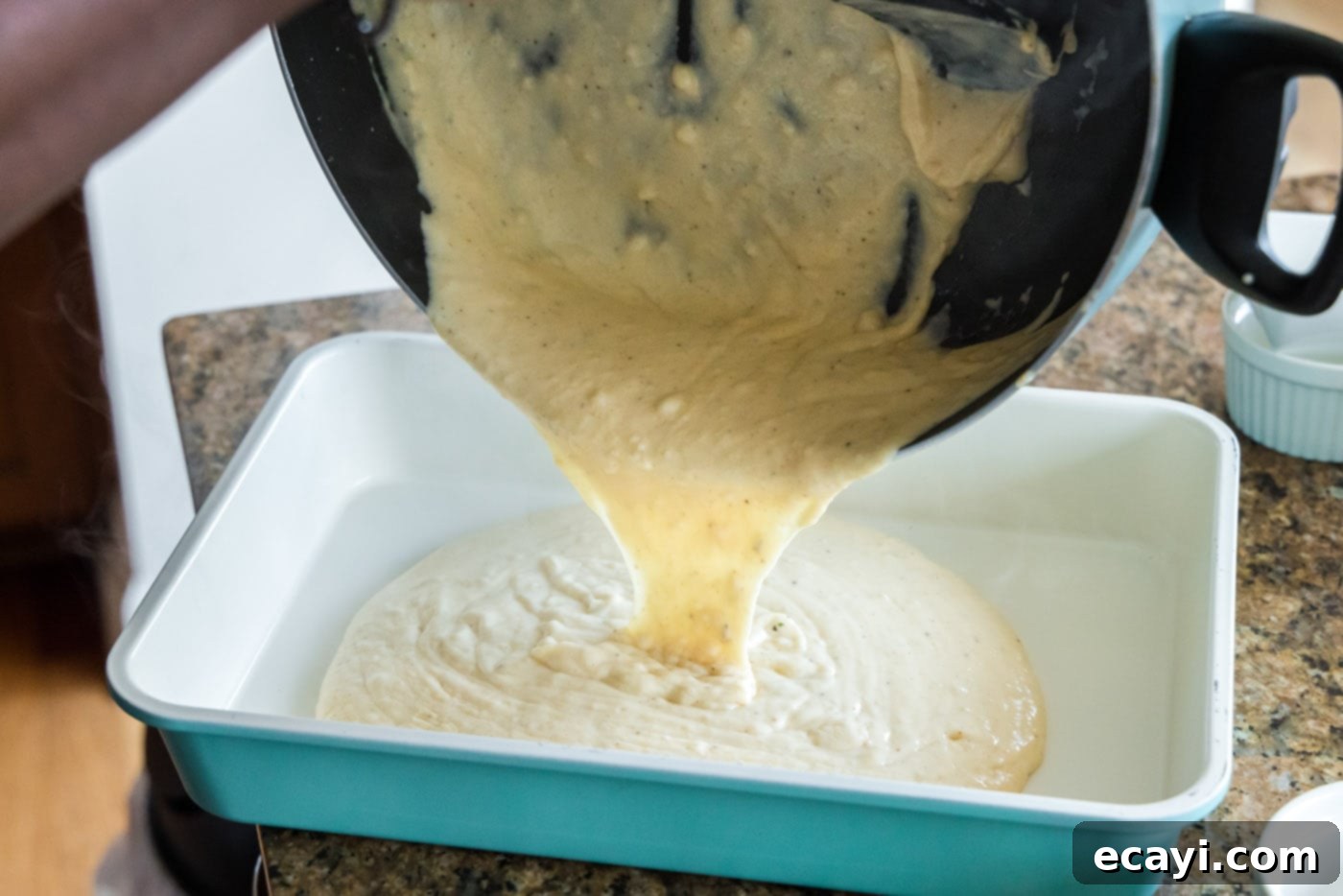 Ocean's Bounty Lasagna 15 Pouring a layer of creamy seafood sauce into the bottom of a baking dish.