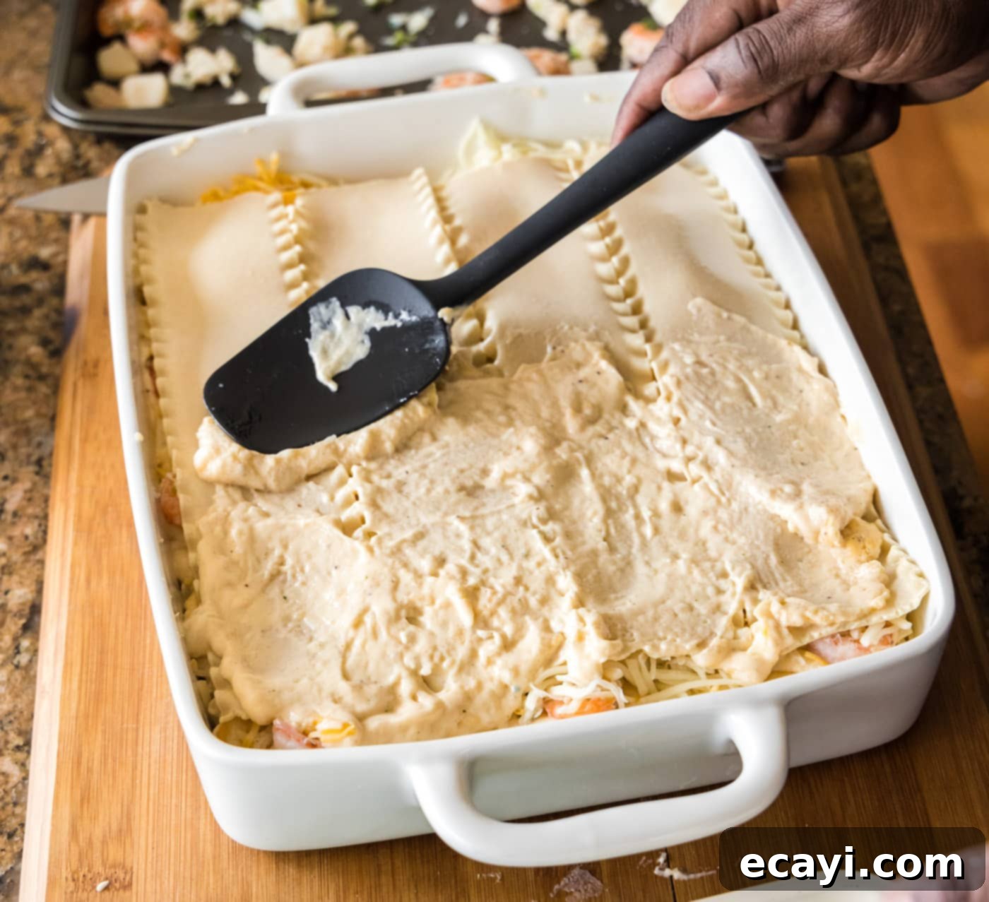 Ocean's Bounty Lasagna 20 Spreading another layer of cream sauce over lasagna noodles.