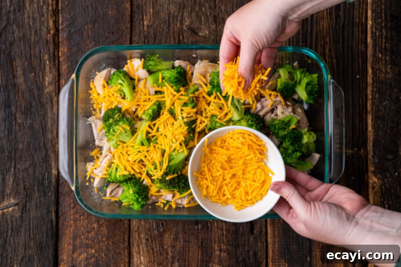 Creamy Chicken Broccoli Bake 7 sprinkling cheddar cheese on top of broccoli and cheddar