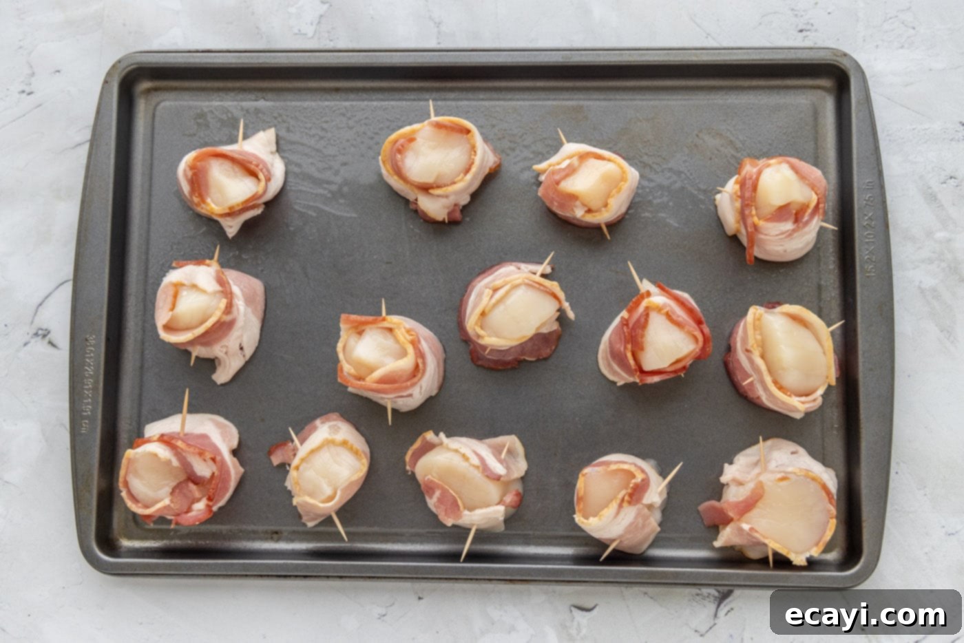 Sea Scallops Draped in Bacon 5 sea scallops wrapped in bacon on a baking shet