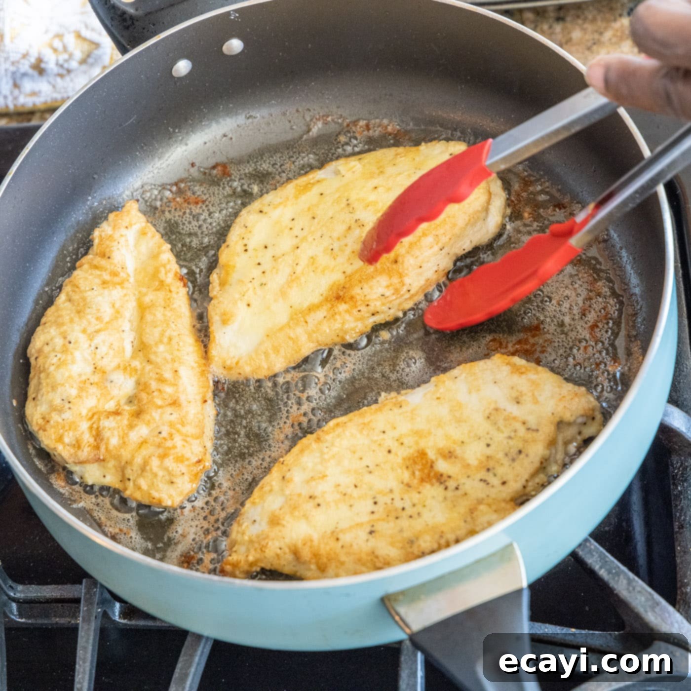 Golden Lemon Chicken 11 chicken breasts in a skillet with tongs