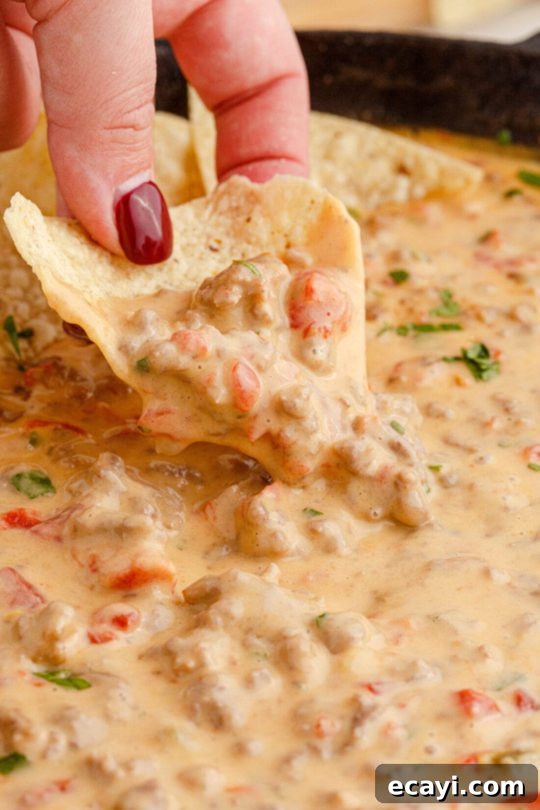 Spicy Creamy Party Queso 3 dipping chip into Rotel Dip, showcasing its creamy texture