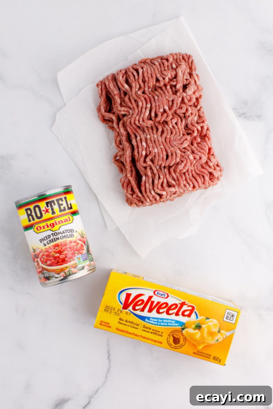 Spicy Creamy Party Queso 4 ingredients for Rotel Dip laid out, including ground beef, Velveeta, and Rotel tomatoes