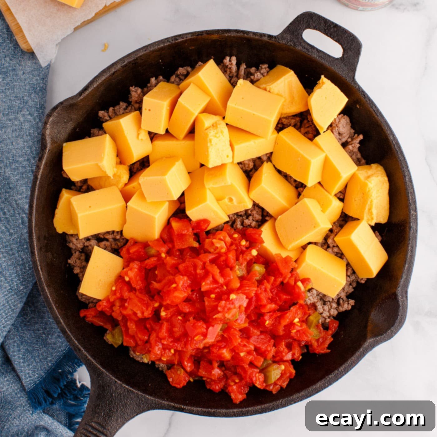 Spicy Creamy Party Queso 6 Rotel tomatoes, Velveeta cheese, and ground beef dip melting in a skillet