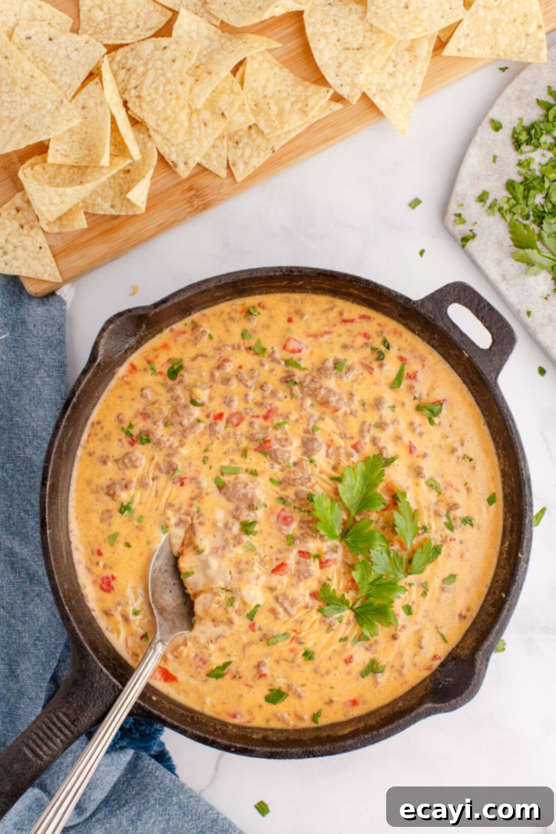 Spicy Creamy Party Queso 7 a pan of Rotel Dip with a spoon, ready to be served