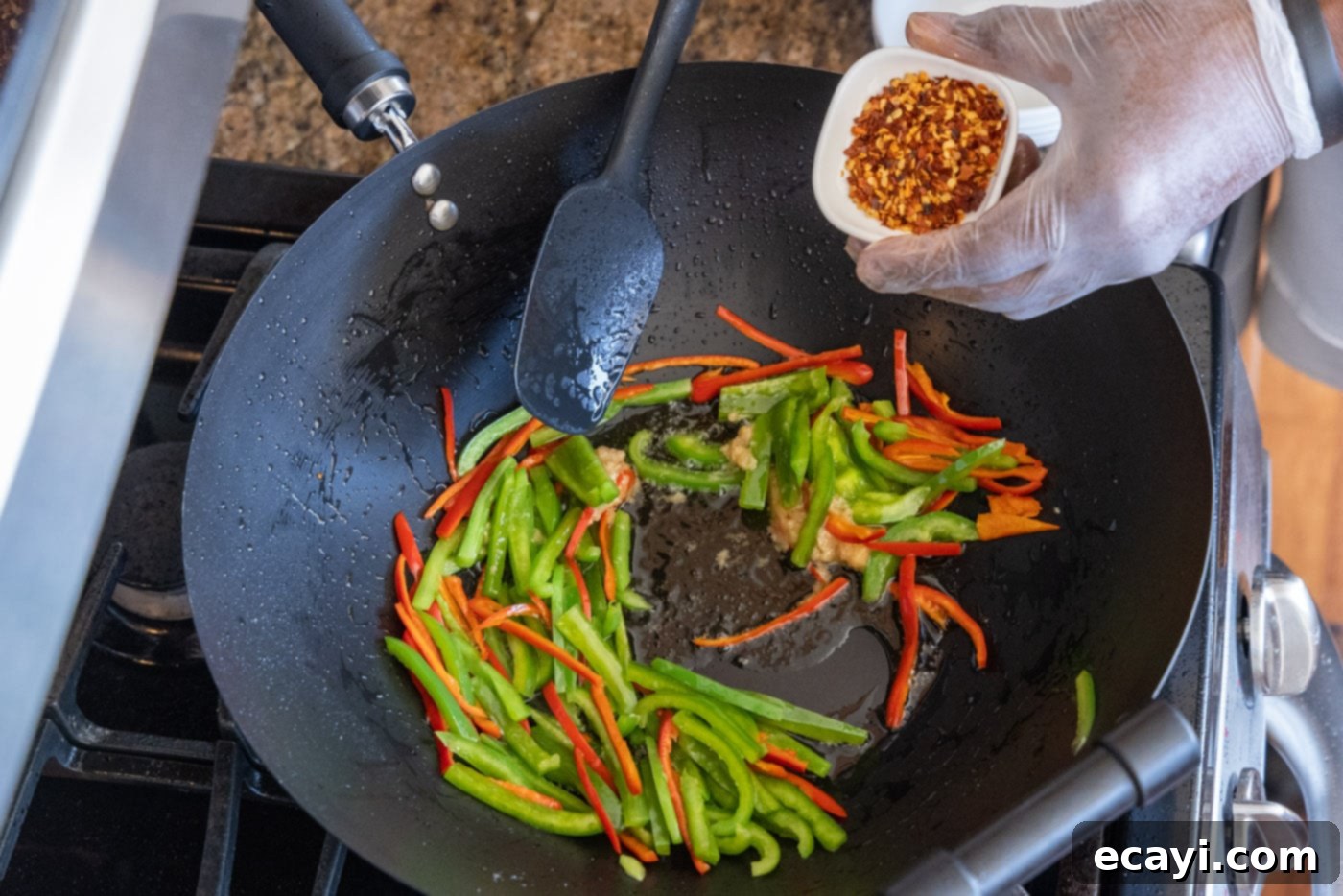 Fiery Szechuan Beef 11 Adding red pepper flakes to the stir-fry mix in a wok