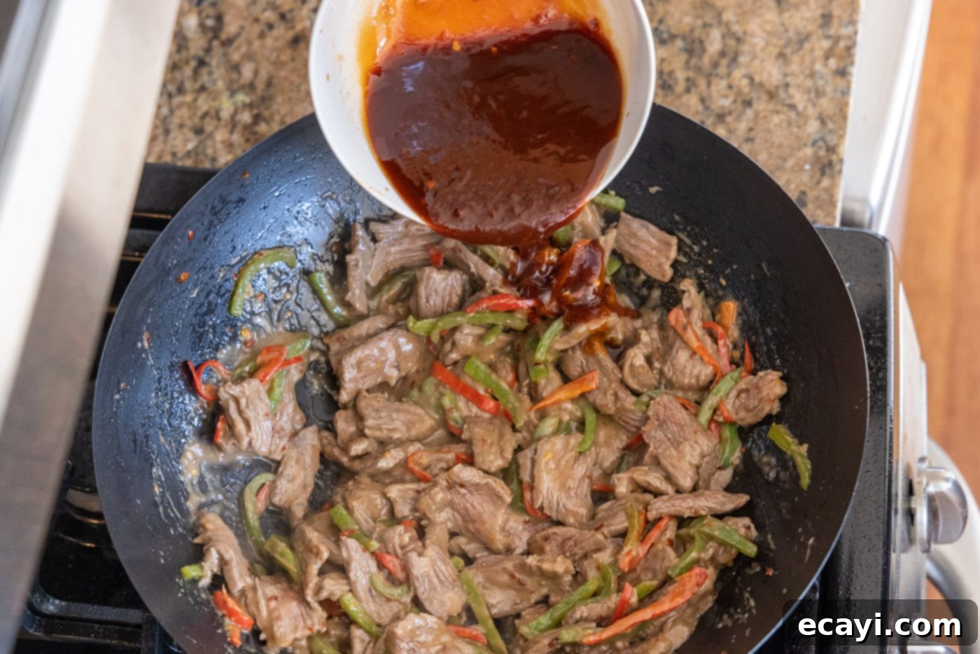 Fiery Szechuan Beef 14 Pouring the prepared sauce over Kung Pao Beef in a wok