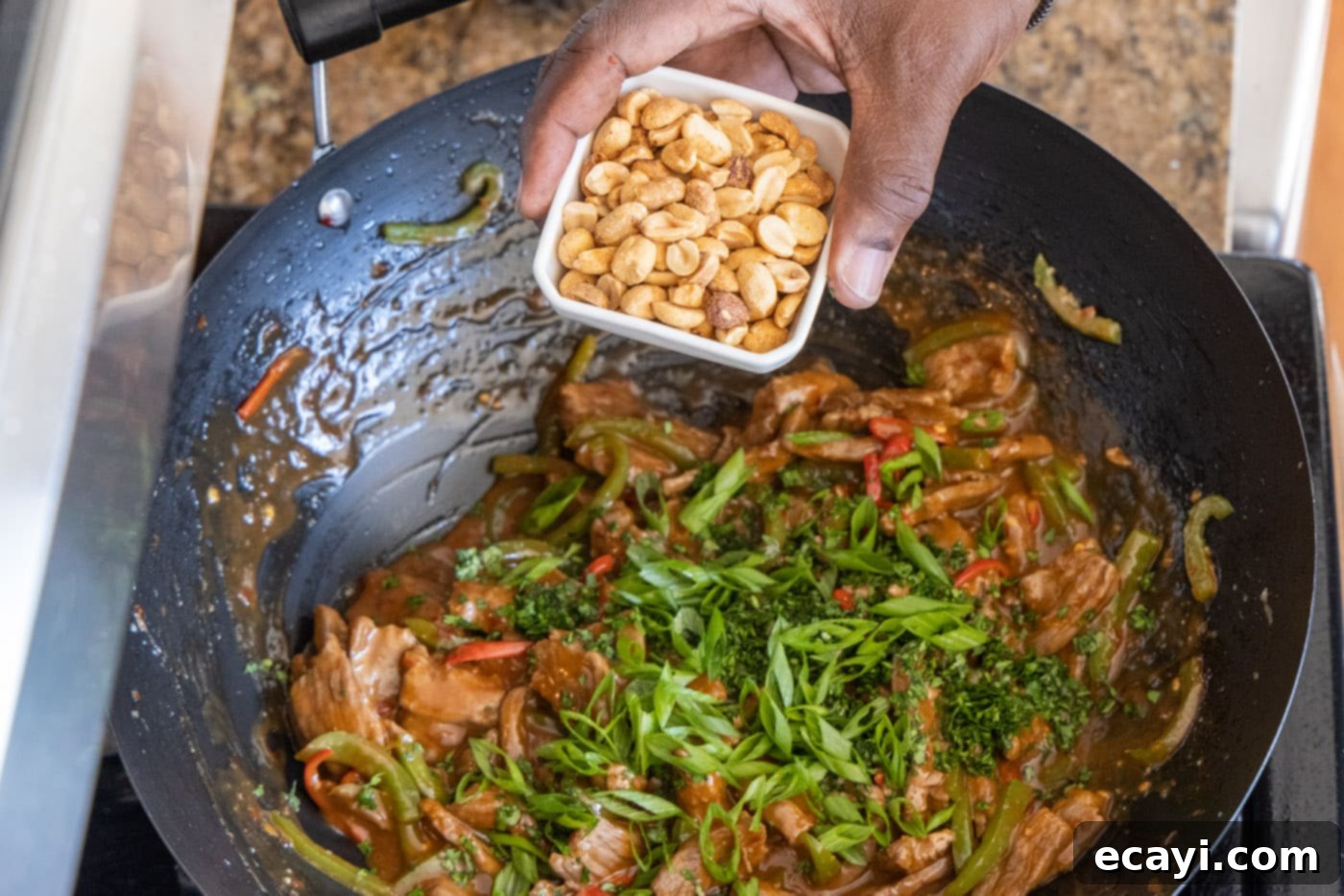 Fiery Szechuan Beef 15 Roasted peanuts being added to the finished Kung Pao Beef in a wok