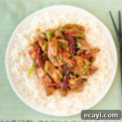 Fiery Szechuan Beef 17 Kung Pao Beef over rice in a bowl, garnished with green onions and peanuts