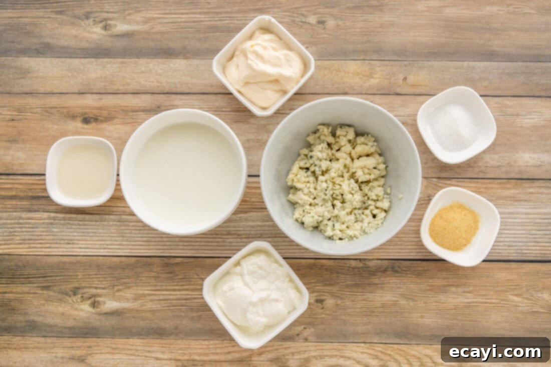 Classic Blue Cheese Dressing 4 A collection of ingredients laid out for making blue cheese dressing, including a block of blue cheese, a carton of buttermilk, and jars of mayonnaise and sour cream.