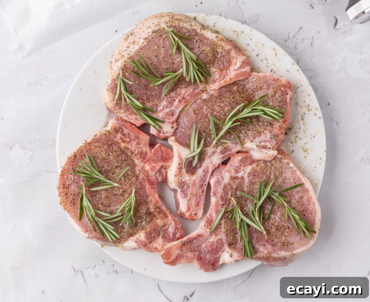 Meltingly Tender Sous Vide Pork Chops 6 pork chops with rosemary sprigs coated in a wet rub
