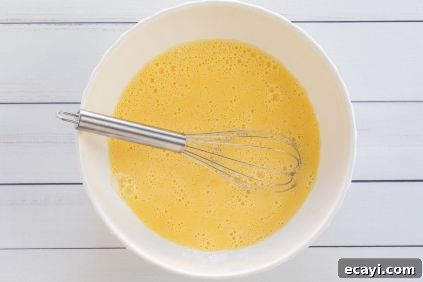 Savory Egg Custard Pie 5 Whisked egg and milk mixture in a large glass bowl, ready for quiche filling.