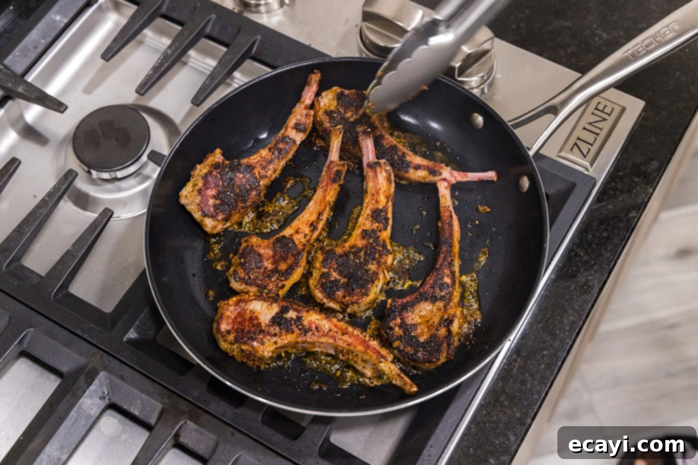 Tender Oven-Baked Lamb Chops 9 A lamb chop being flipped in a hot skillet with tongs, showing a beautiful sear.