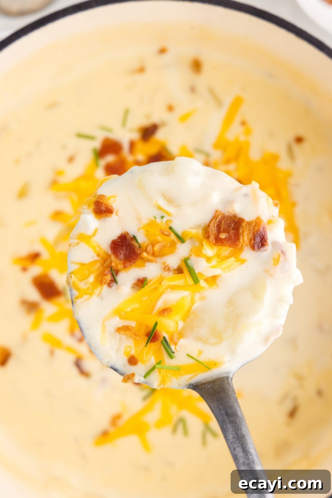 Loaded Baked Potato Soup 15 Ladle lifting creamy baked potato soup from a large pot, showcasing its rich texture and toppings of bacon, cheese, and chives, ready to serve