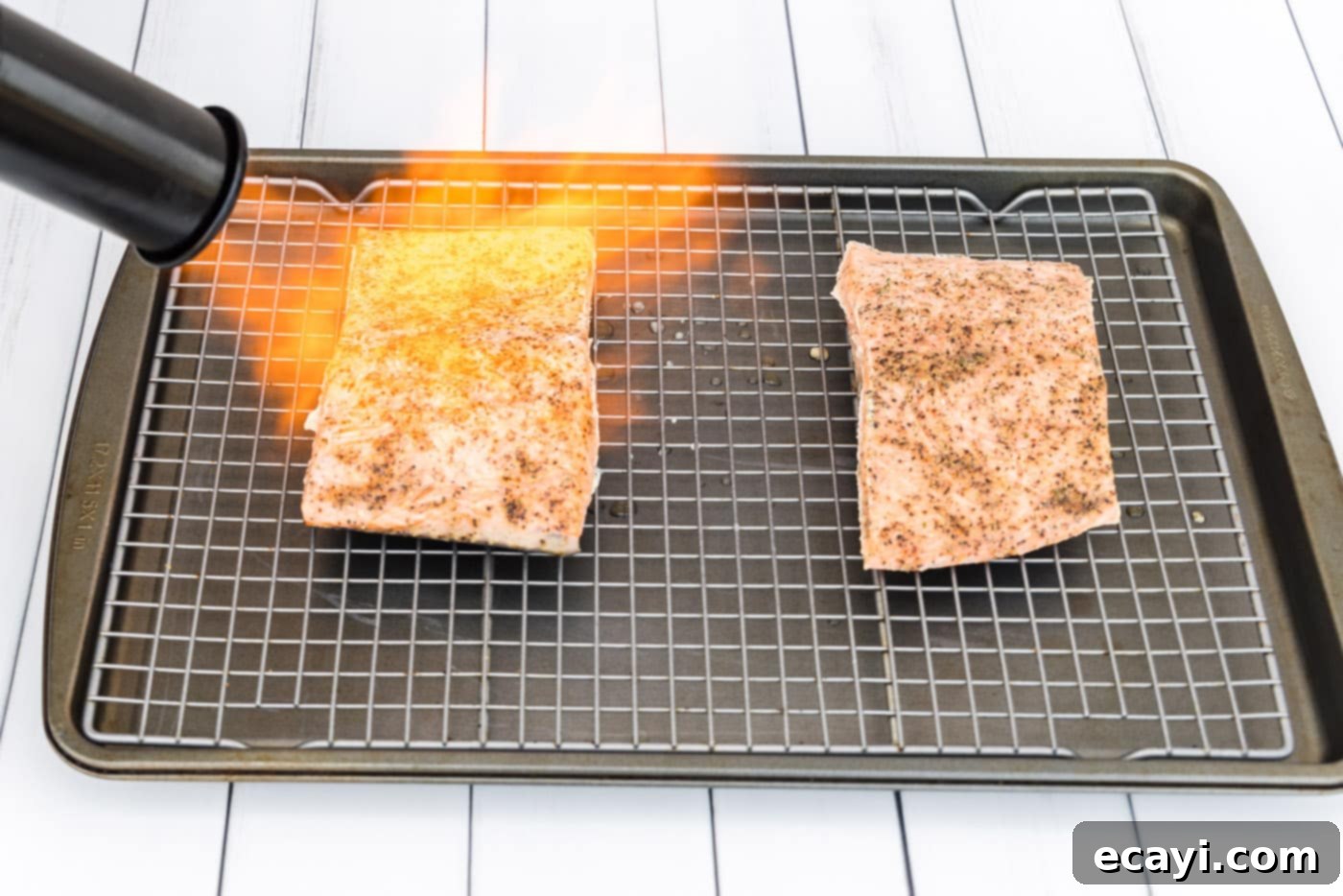 Perfect Sous Vide Salmon 11 A chef using a kitchen torch to sear the delicate exterior of cooked sous vide salmon fillets, creating a crisp finish.