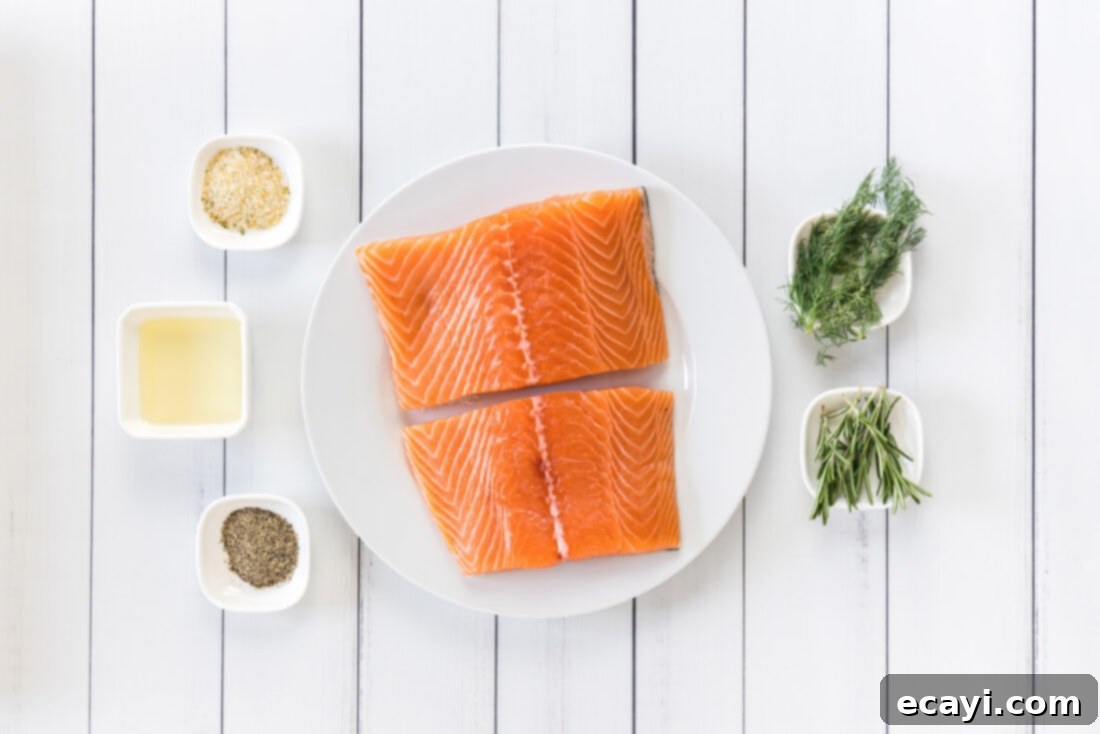 Perfect Sous Vide Salmon 4 A selection of fresh ingredients including salmon fillets, olive oil, garlic salt, black pepper, rosemary, and dill, laid out for sous vide salmon preparation.