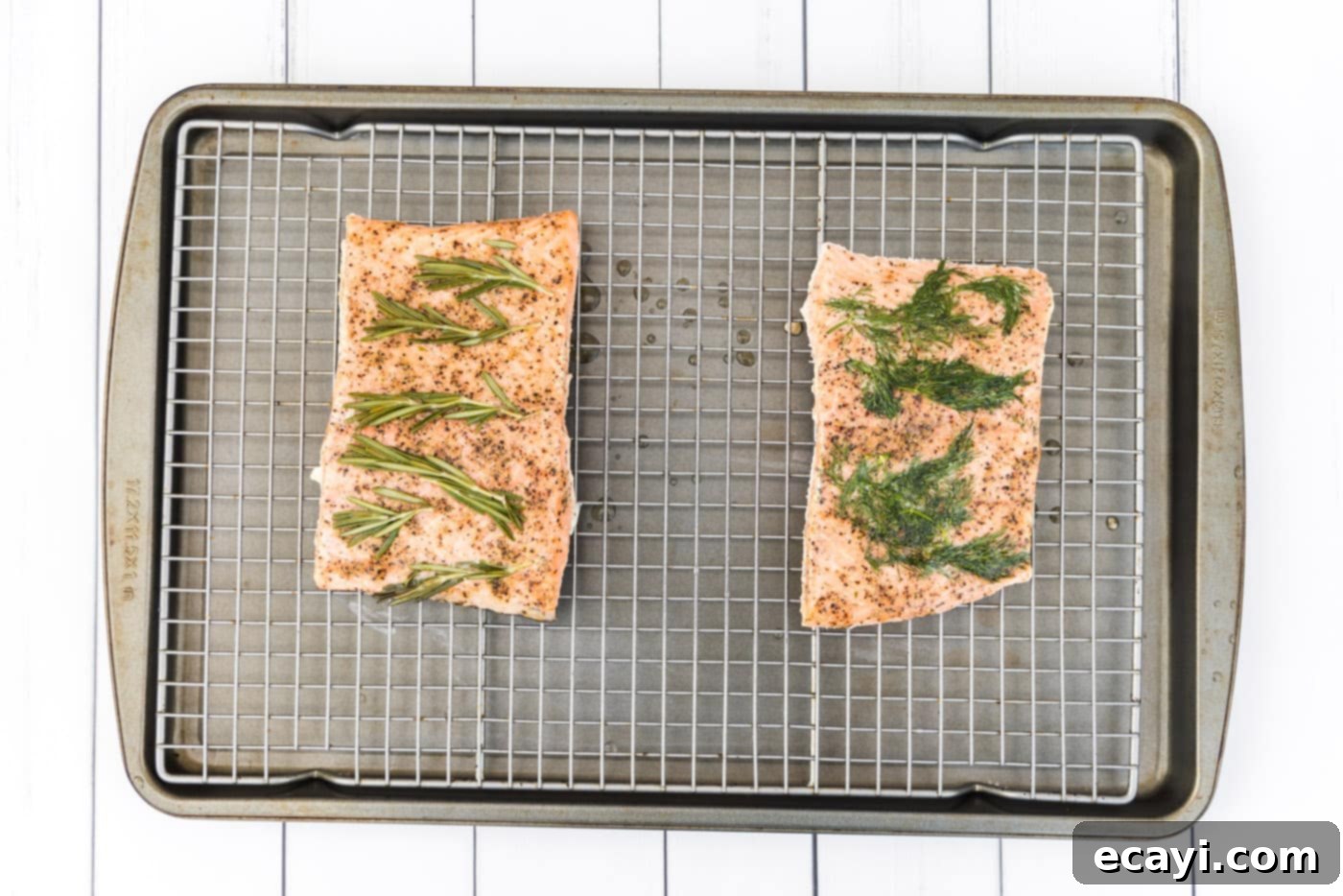 Perfect Sous Vide Salmon 10 Cooked sous vide salmon fillets resting on a wire cooling rack after being removed from their vacuum bags, with discarded herbs nearby.