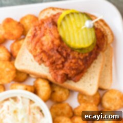 Nashville Hot Chicken 11 Piece of Nashville Hot Chicken resting on white bread, garnished with pickles.