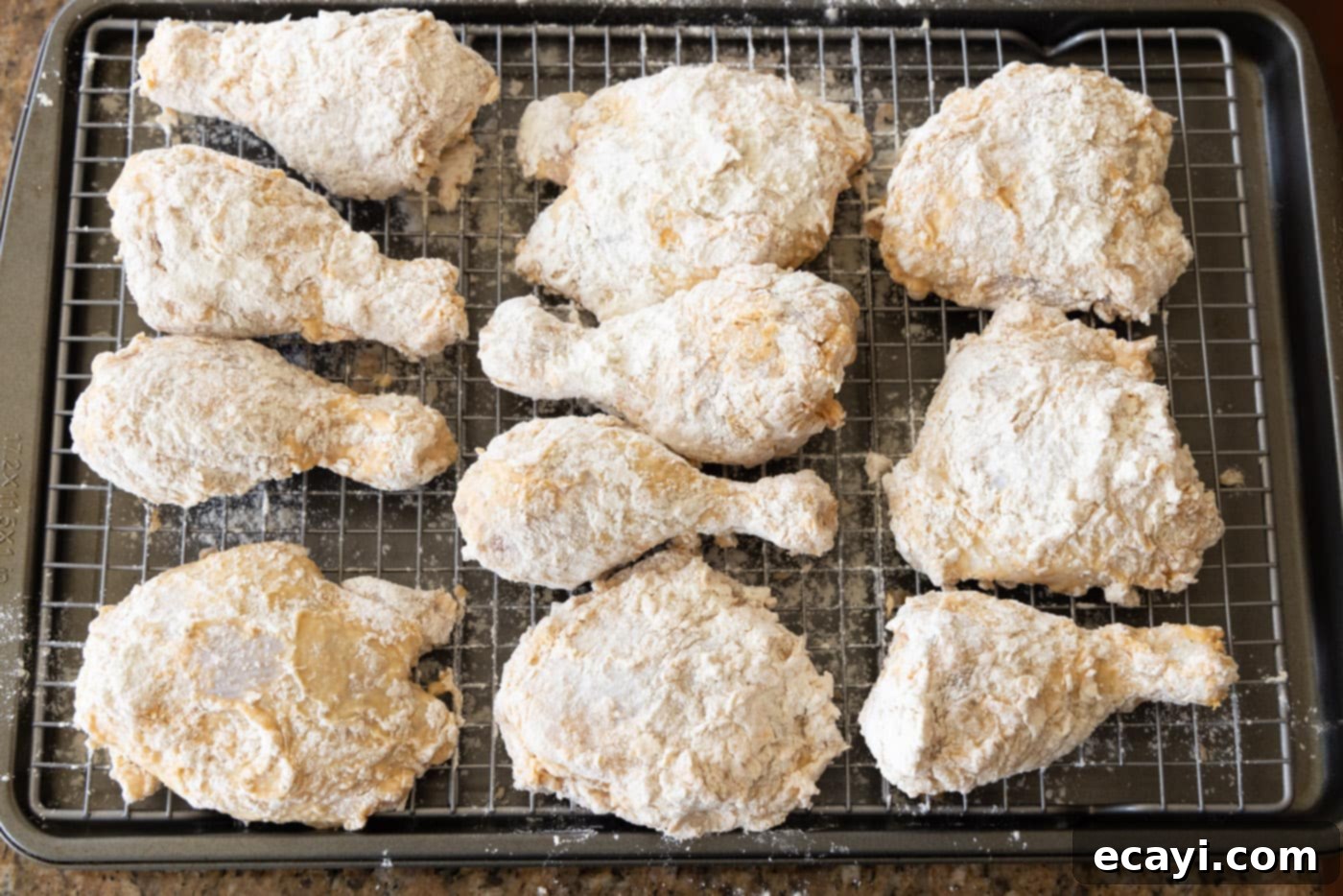 Nashville Hot Chicken 8 Breaded chicken thighs and legs resting on a wire rack on a baking sheet, prepped for frying for Nashville Hot Chicken.