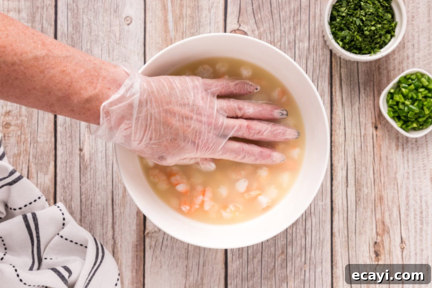 Zesty Lime Shrimp Ceviche 11 hand pressing down on shrimp in a bowl with citrus juice