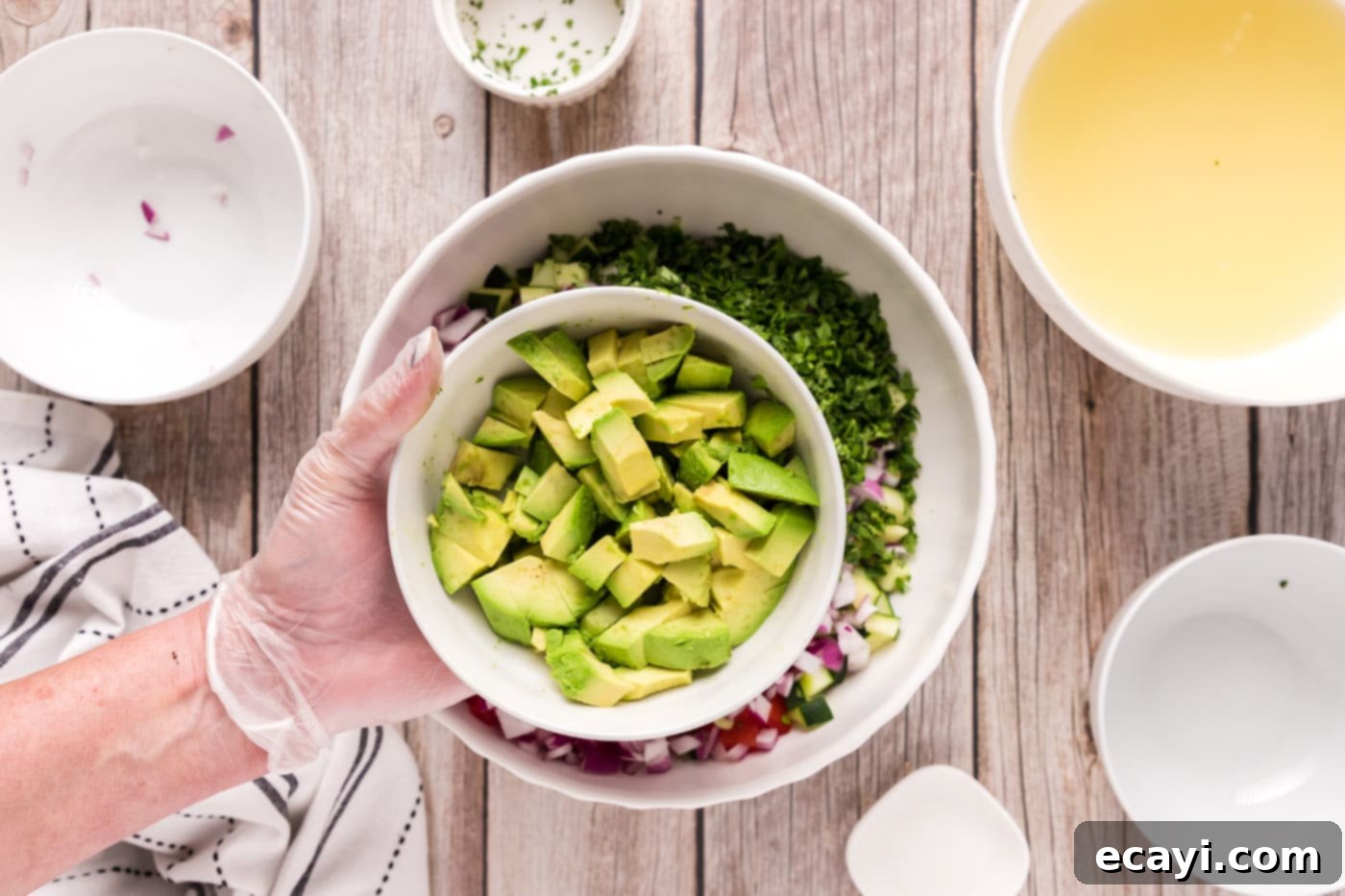 Zesty Lime Shrimp Ceviche 12 adding avocado to bowl of diced fruits and vegetables with shrimp