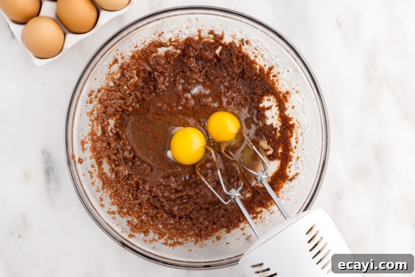 Peanut Butter Brownie Bliss 7 adding eggs to brownie batter in a mixing bowl